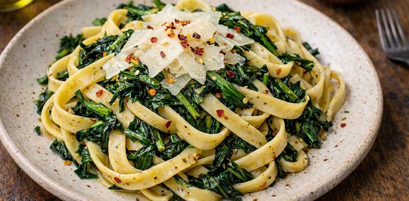 fettuccine with dandelion greens on a rustic plate