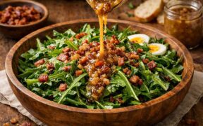 dandelion salad with hot bacon dressing in a wooden bowl