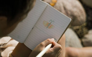 kid drawing a butterfly in her journal